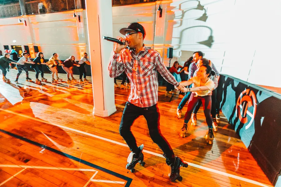 Osiris skating at a rolling rink with a microphone in hand.
